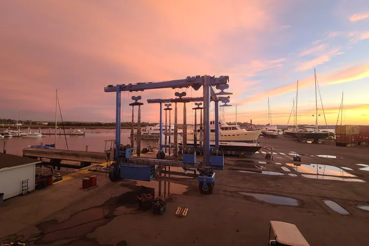 Boatyard travel lift at sunrise with hauled-out yachts in the yard