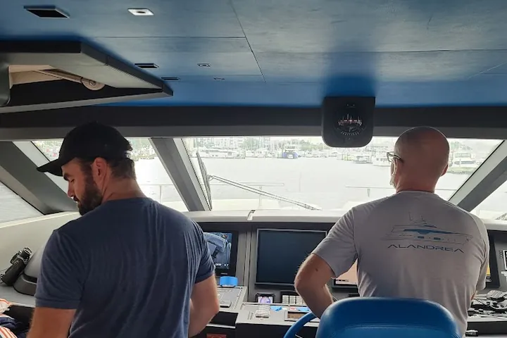 Two crew members working at the helm consoles of a motor yacht