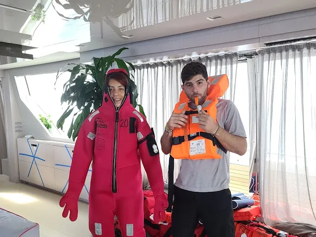 Crew members trying on an immersion suit and lifejacket during safety equipment familiarisation